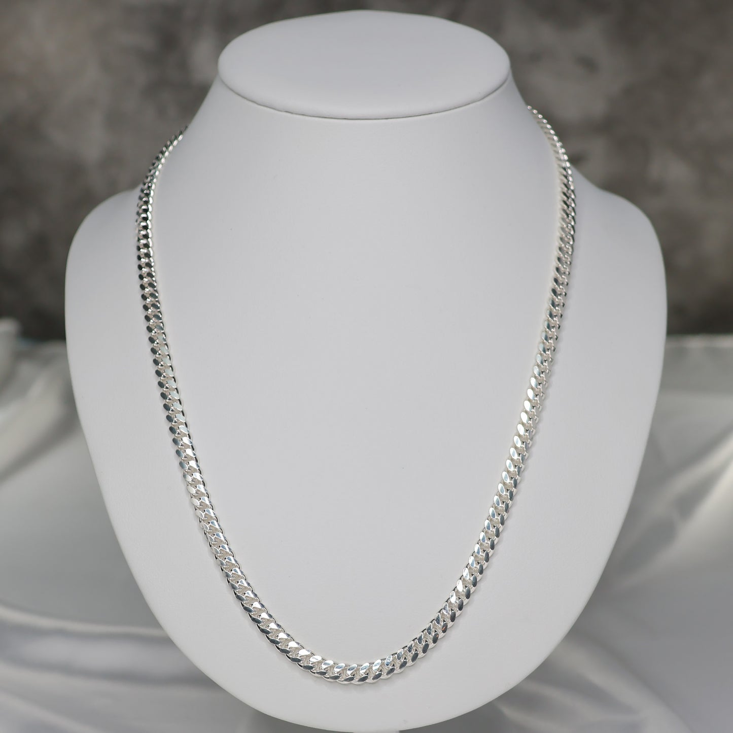 22 inch silver curb chain displayed on a white bust for elegant jewelry presentation