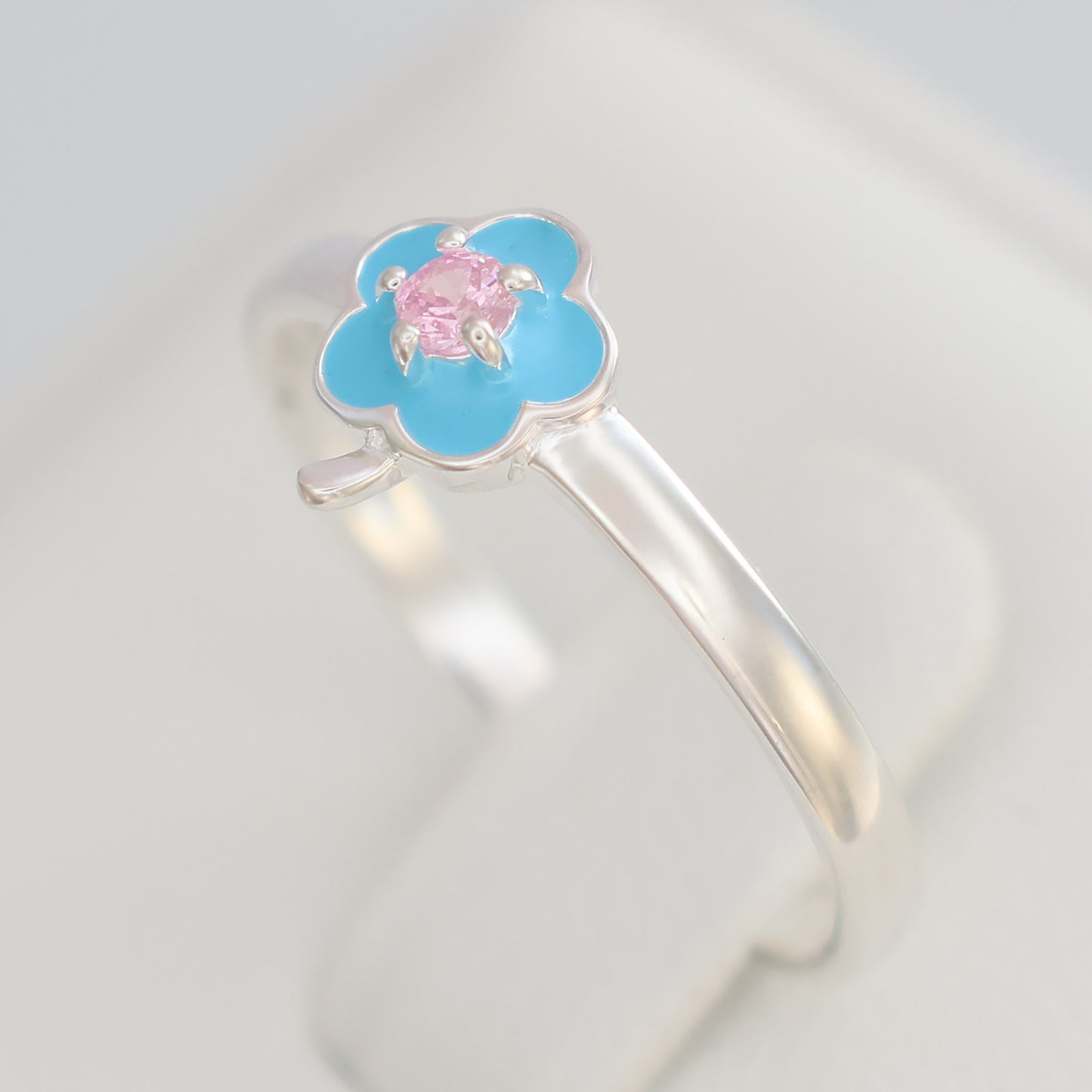 Floral design silver ring featuring a blue flower and pink gemstone center for a delicate look