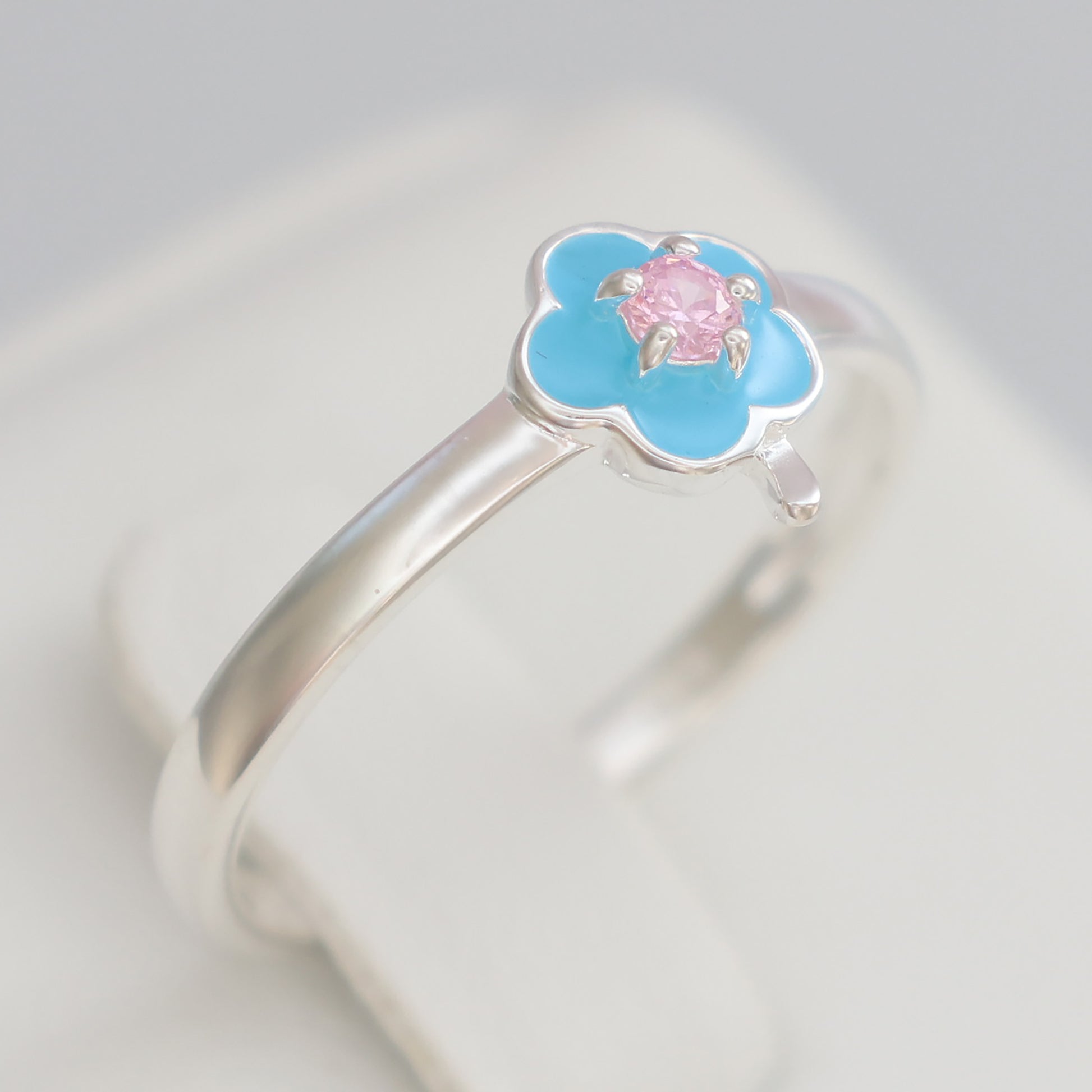 Floral design silver ring with a blue enamel flower and a pink gemstone accent