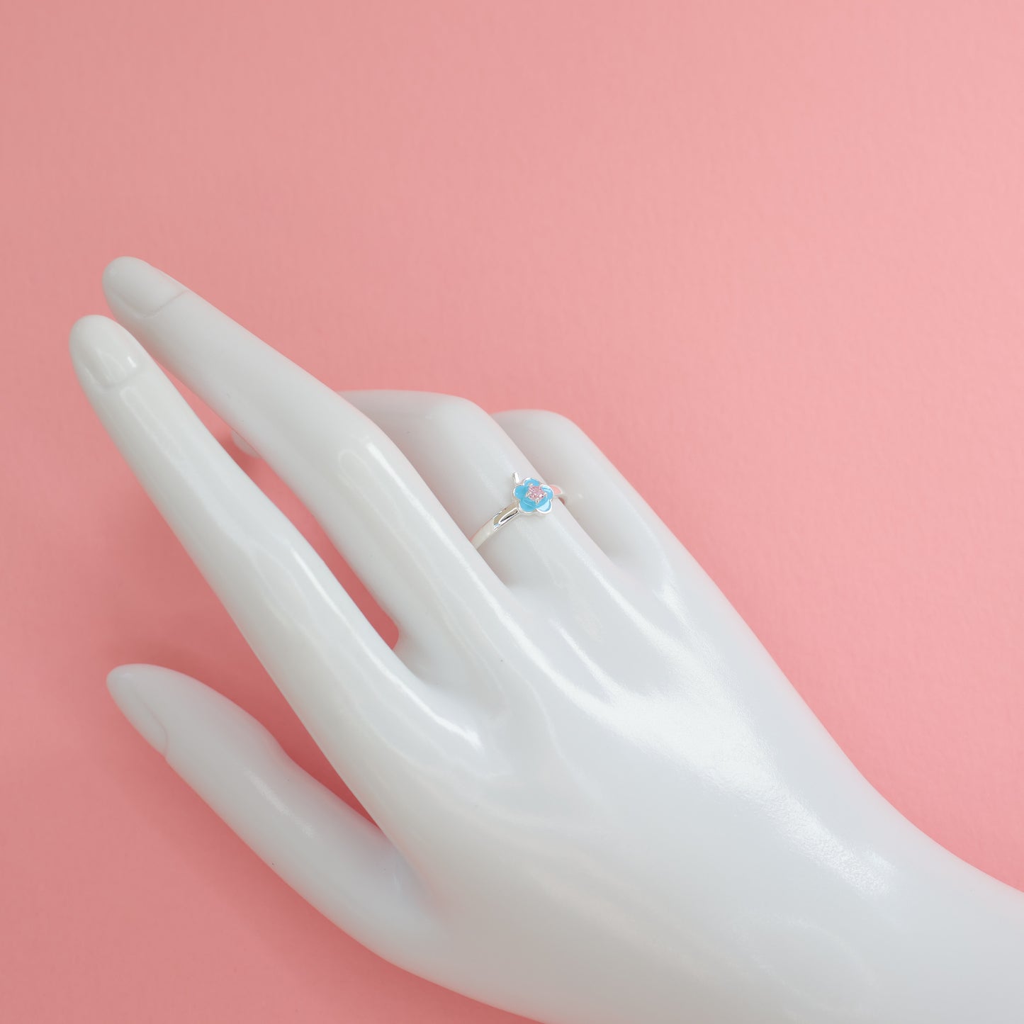 Floral design silver ring featuring a turquoise center stone displayed on a hand mannequin
