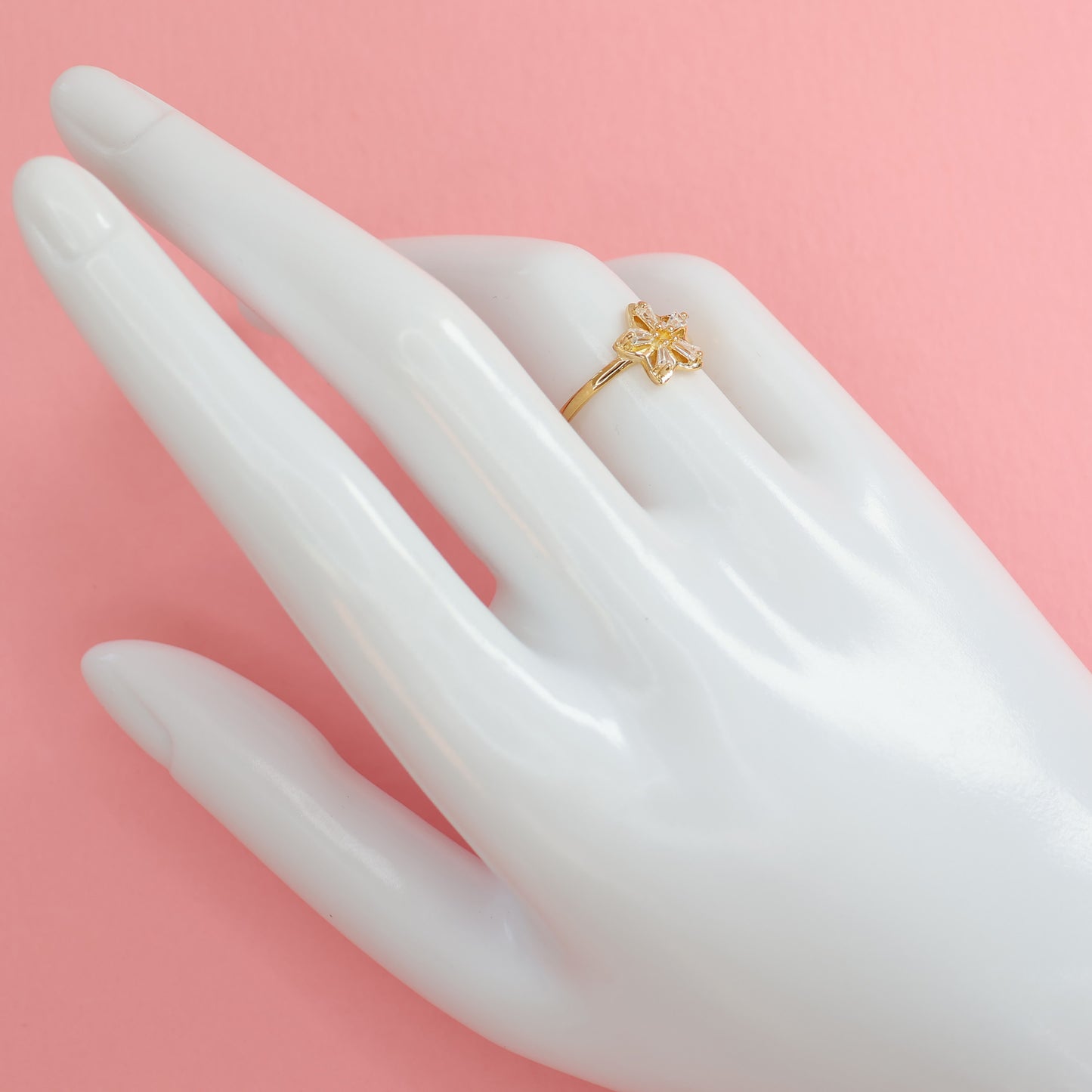 Elegant flower design gold plated ring displayed on a mannequin hand with a soft pink background