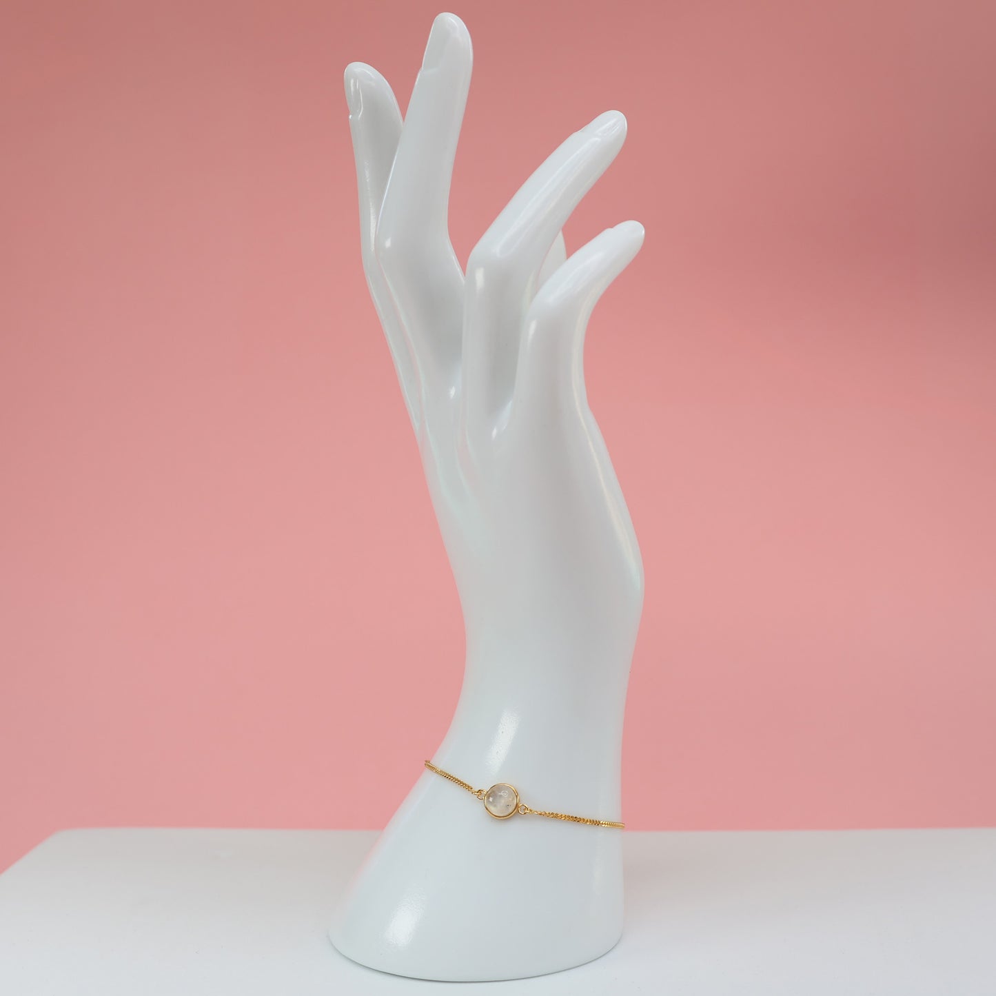 Elegant Gold Moonstone Bracelet displayed on a white hand model against a pink background