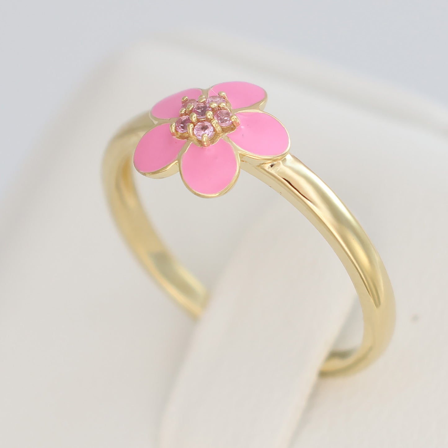 Gold plated pink enamel ring featuring a flower design with sparkling accents