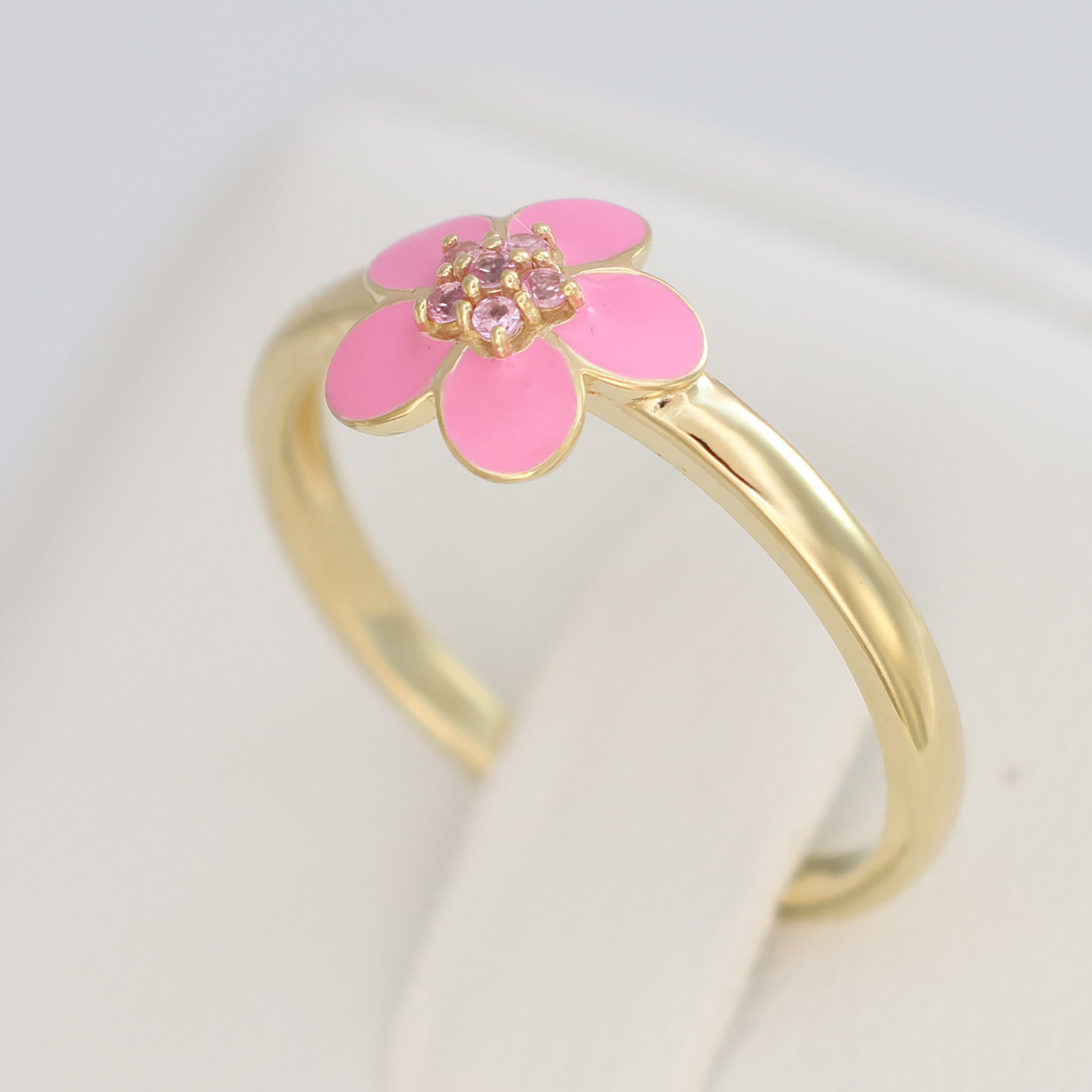 Gold plated pink enamel ring featuring a flower design with sparkling accents