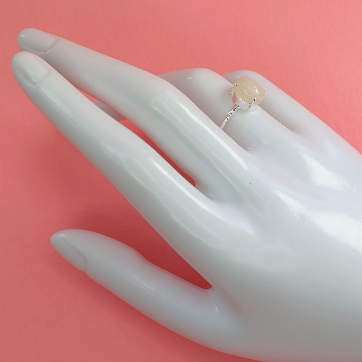 Large moonstone silver ring displayed on a hand model with a soft pink background