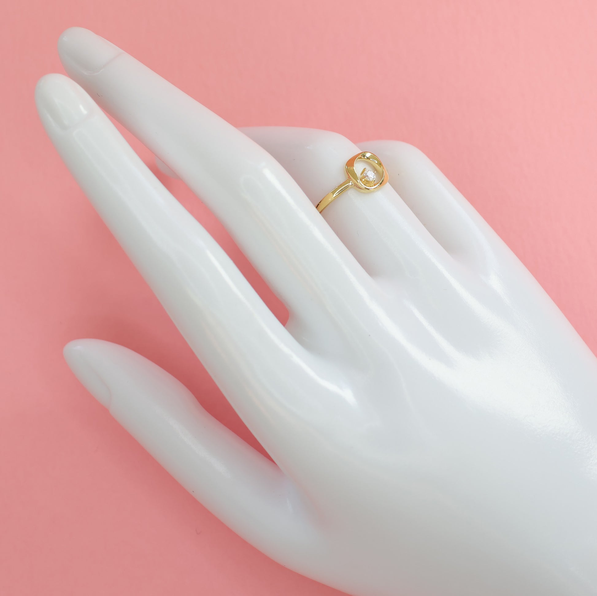 Elegant modern square ring with CZ stone showcased on a hand model against a pink background