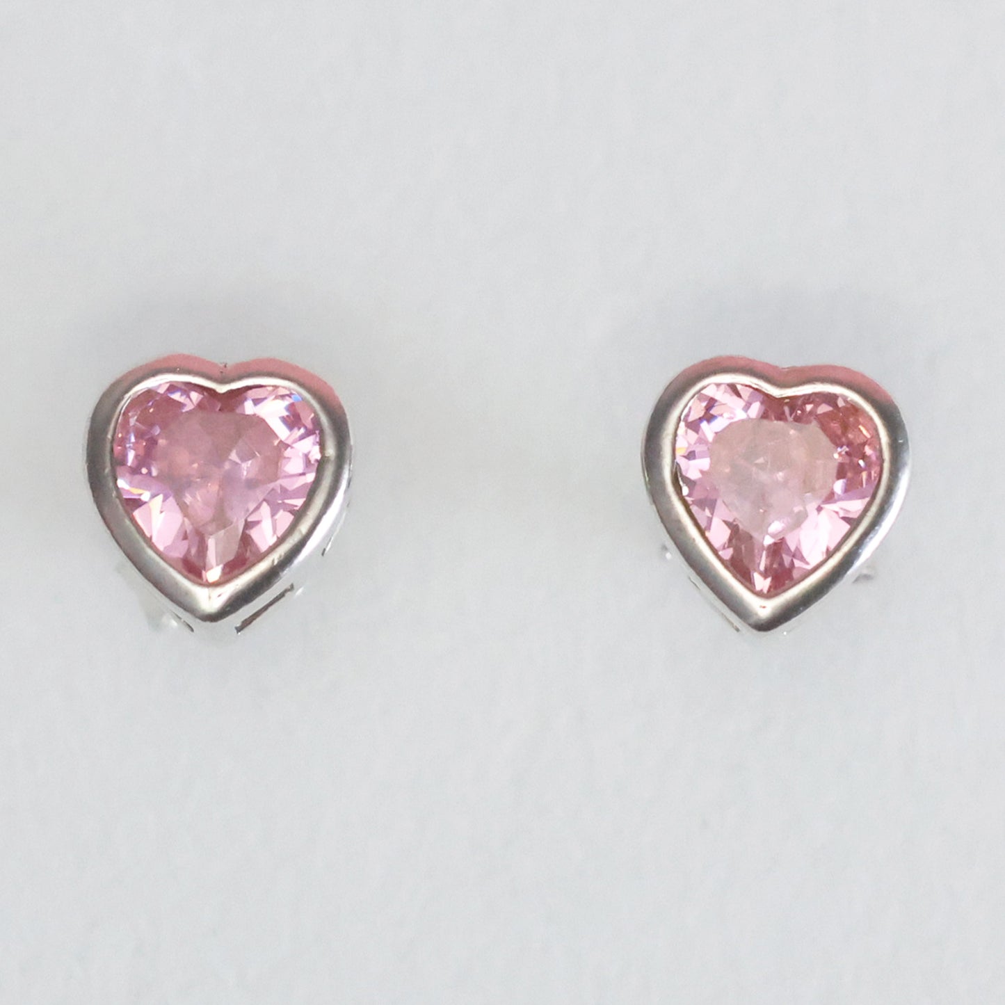 Heart-shaped pink gemstone stud earrings in silver setting for stylish elegance