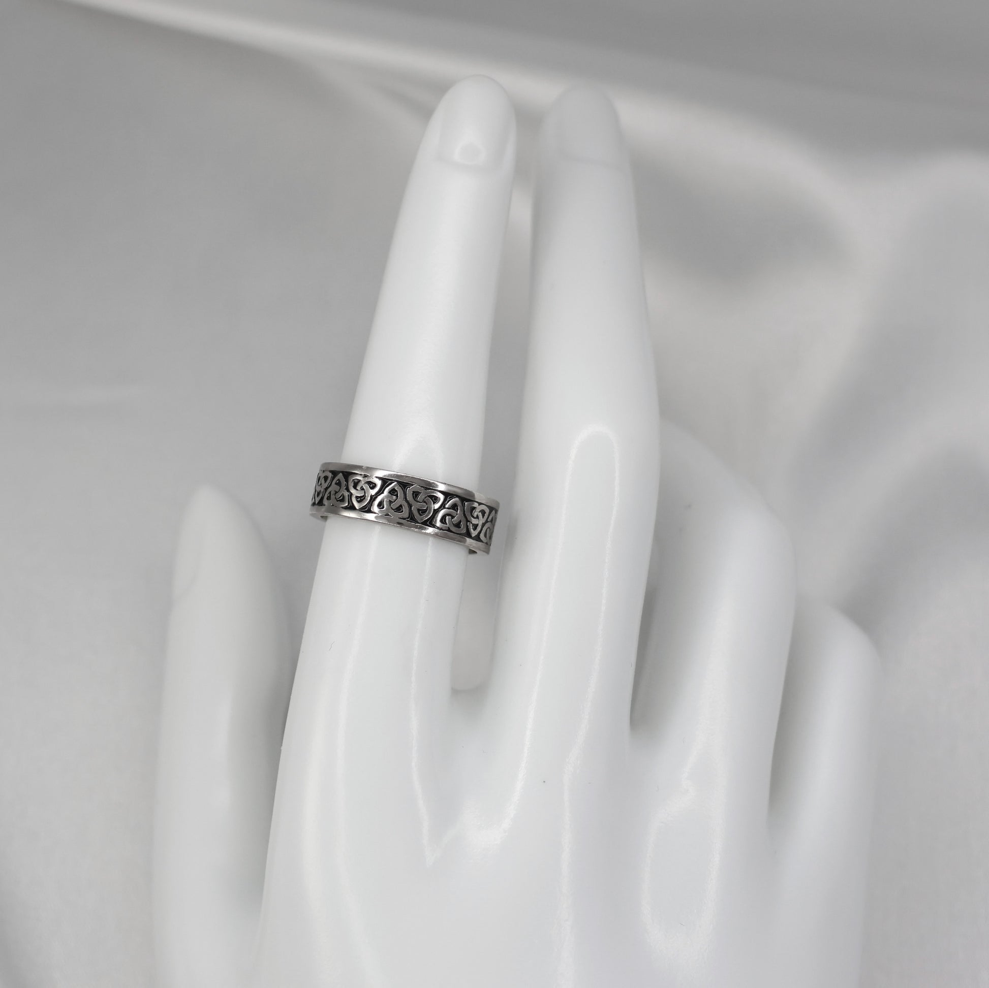 Silver Celtic band ring featuring intricate patterns displayed on a mannequin hand