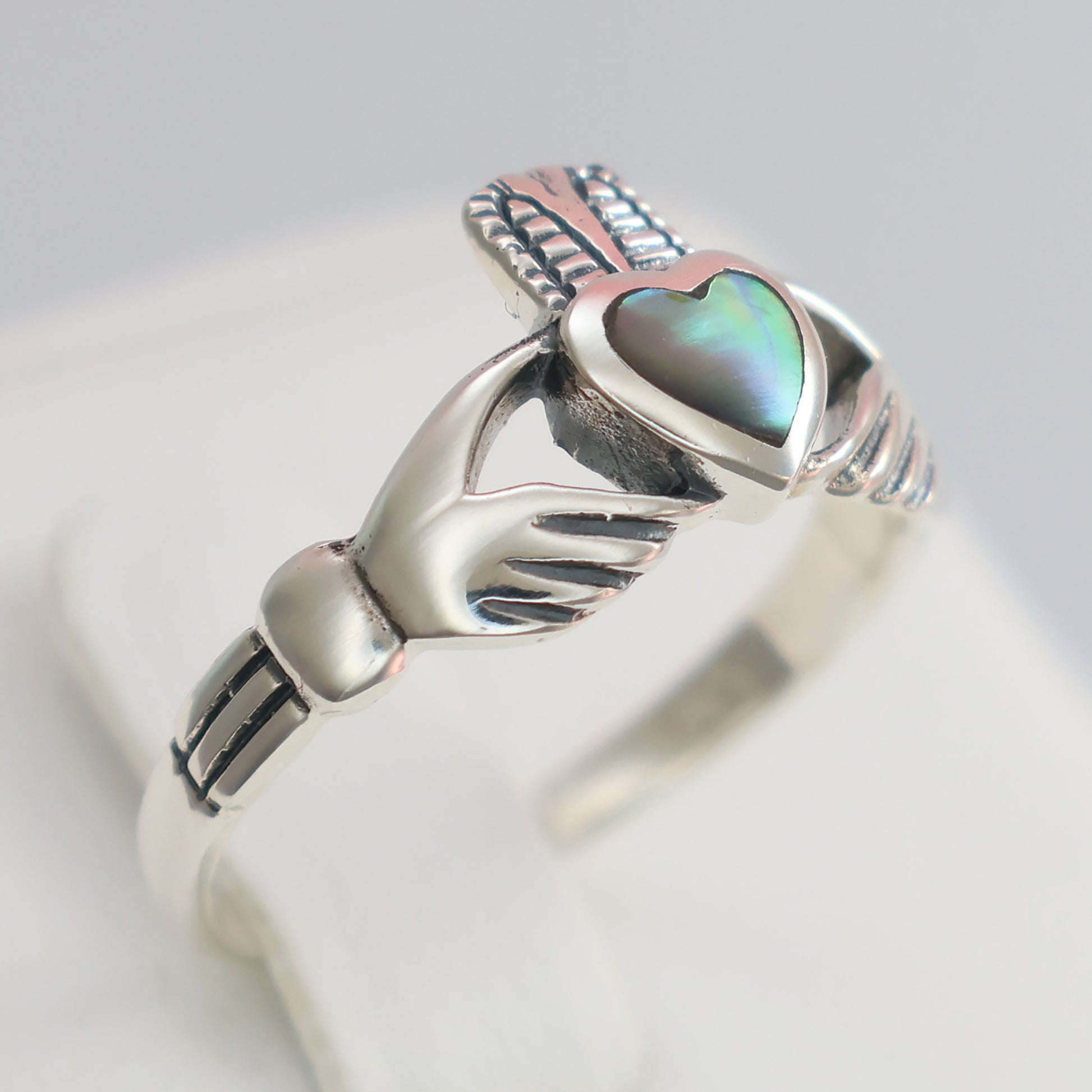 Silver Claddagh Ring featuring a heart-shaped stone held by two hands on a polished band