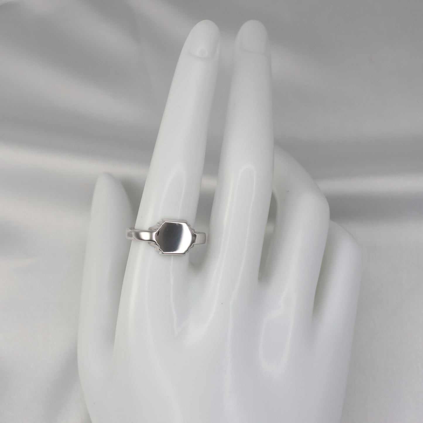 Silver hexagon signet ring displayed on a mannequin hand showcasing its elegant design