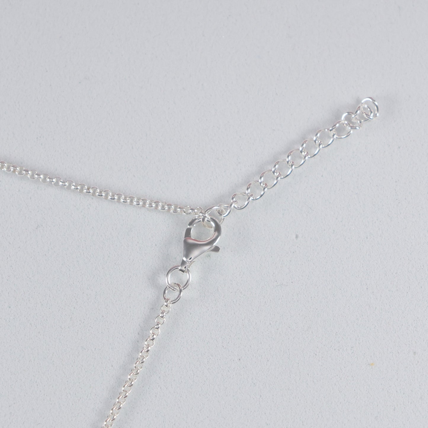 Close-up of silver interlocking hoop necklace clasp and chain detail for elegant jewelry styling