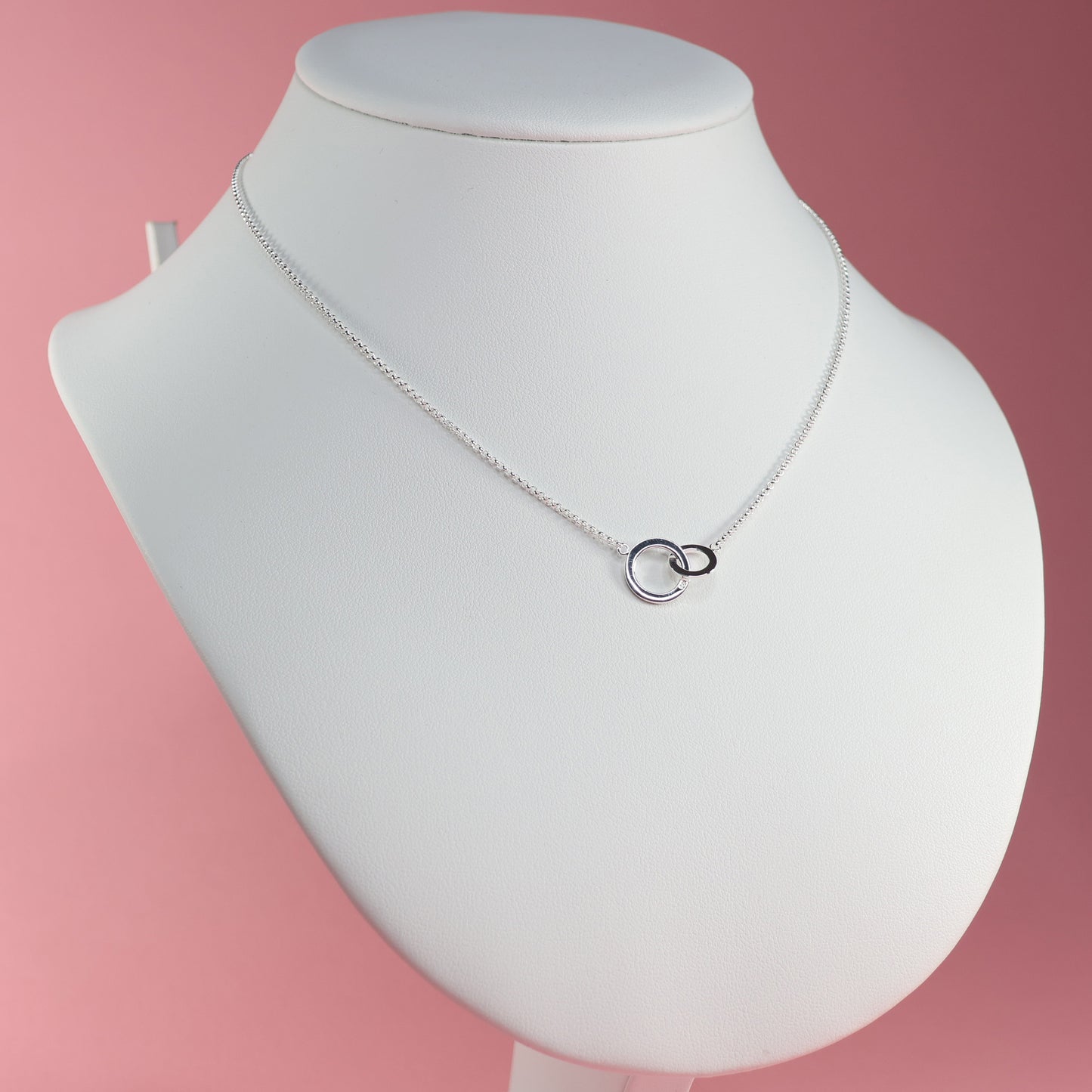 Elegant silver interlocking hoop necklace on a display bust for a stylish look