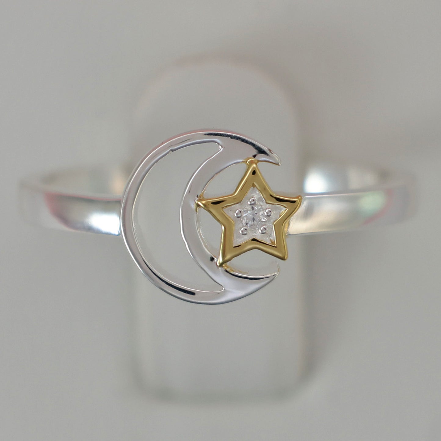 Silver moon and star ring featuring a gold star design with sparkling accents