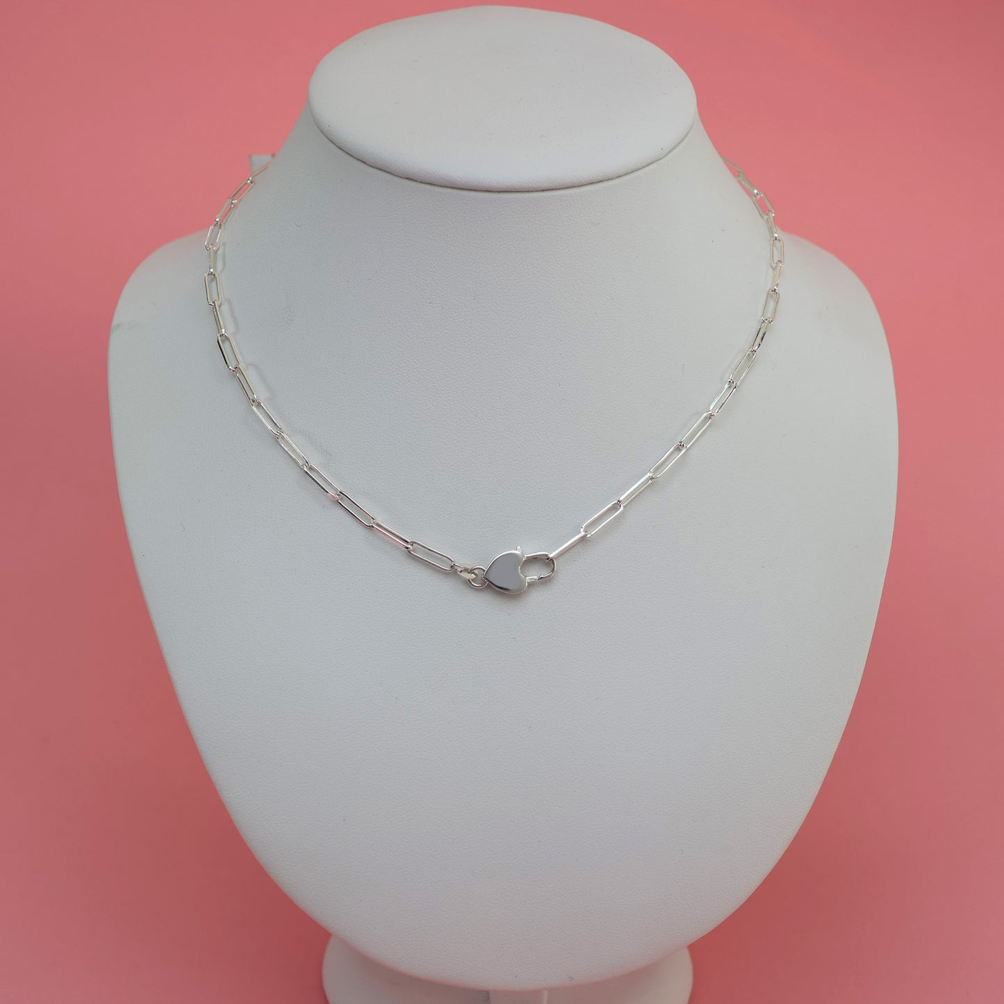 Stylish silver necklace with heart clasp displayed on a jewelry stand
