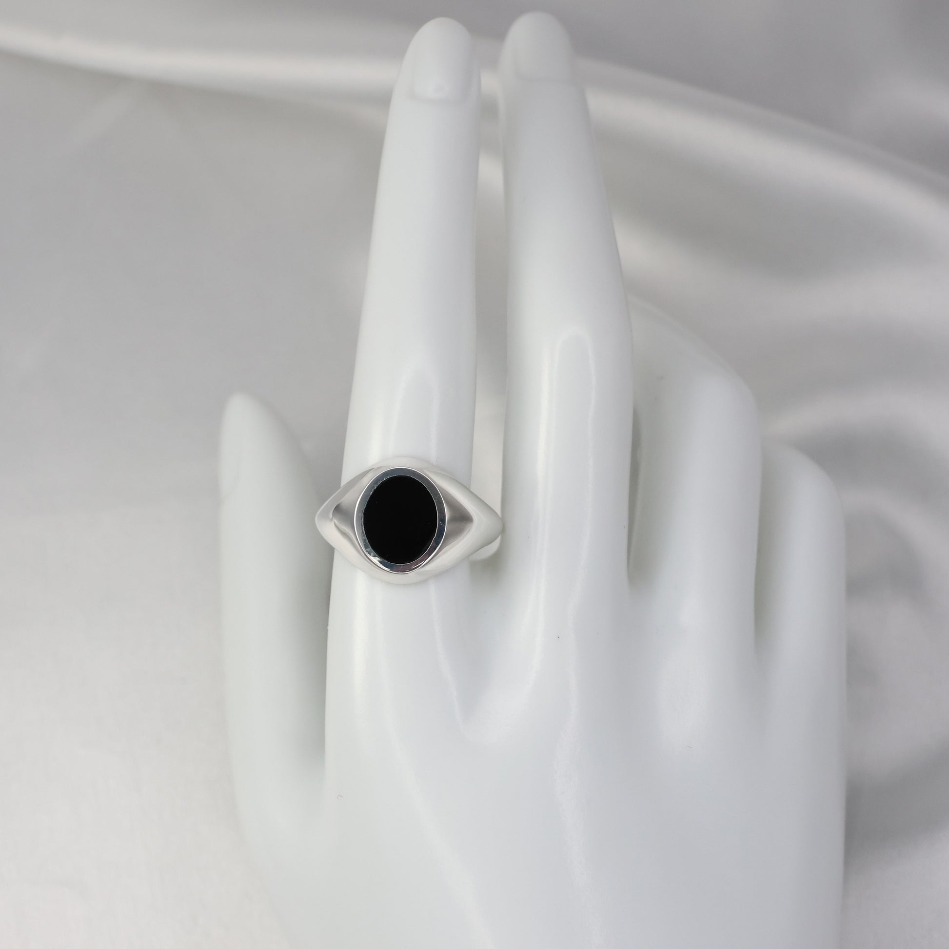 Silver signet ring with an eye design and black stone in a polished finish