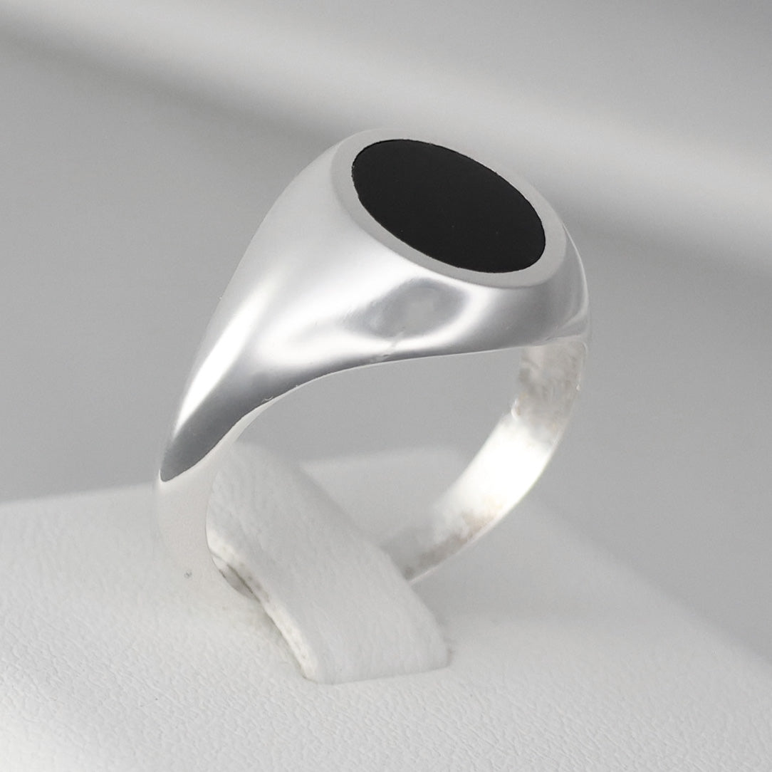 Stylish silver signet ring with a smooth black oval stone on a polished band