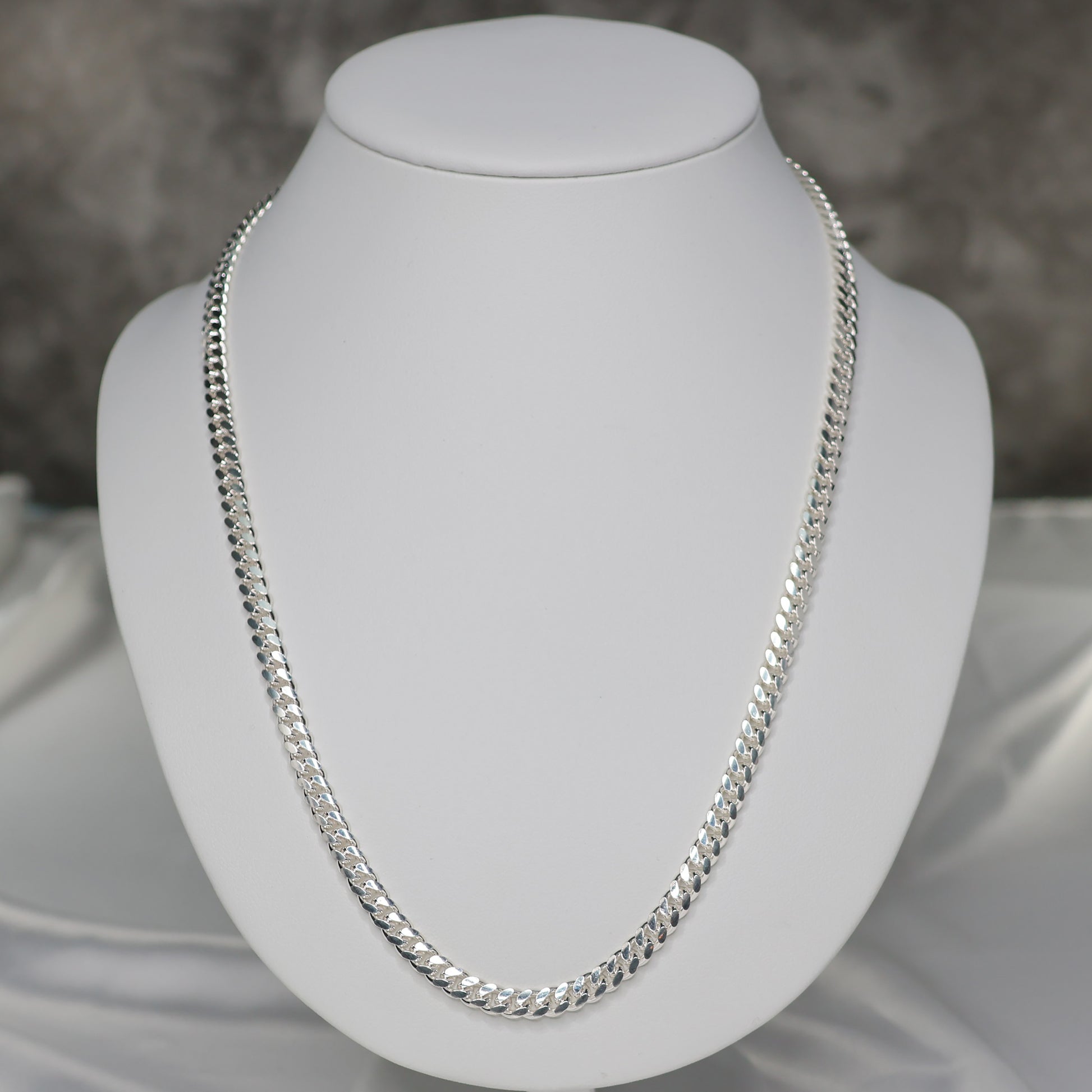 22 inch silver curb chain displayed on a white bust for elegant jewelry presentation