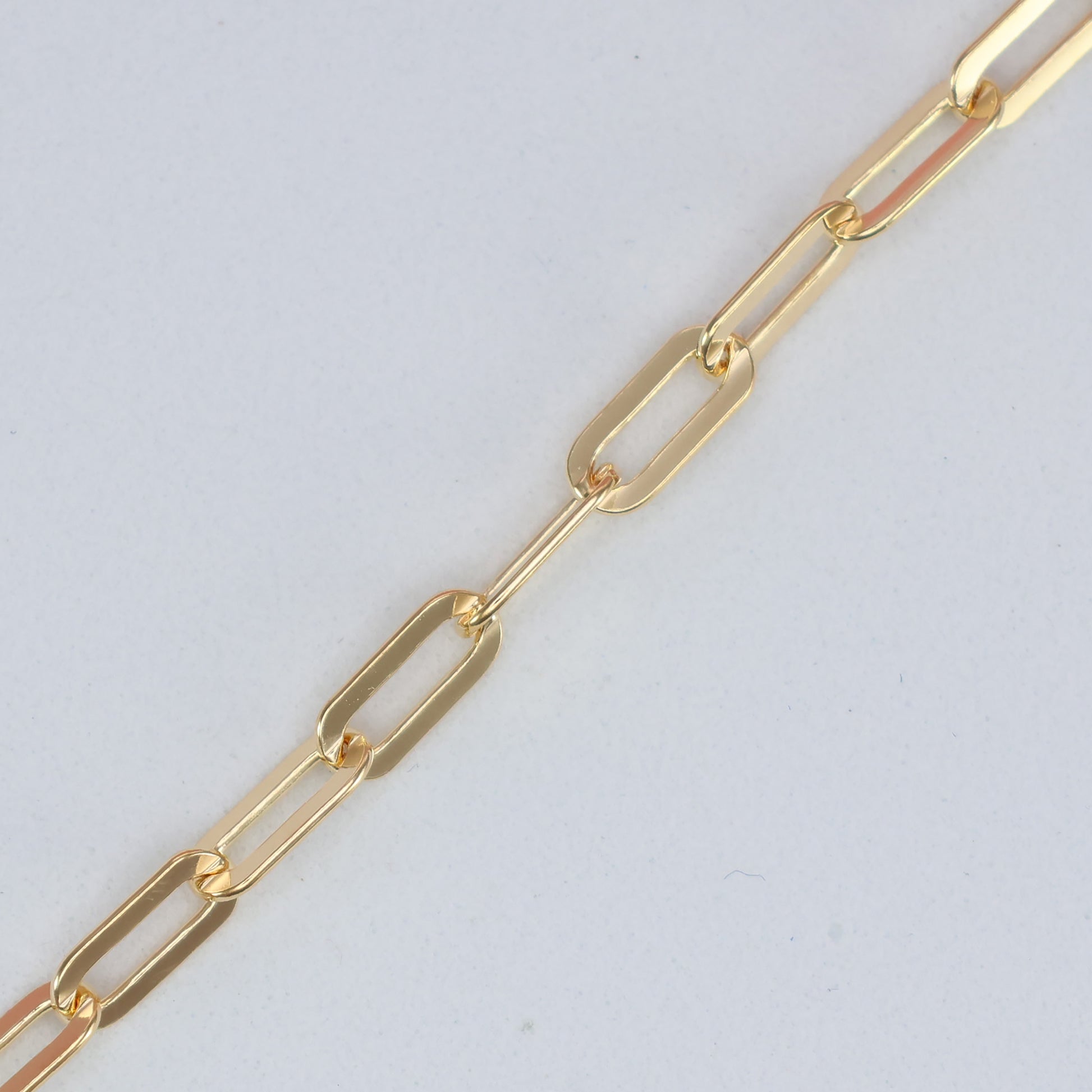Close-up of a gold plated paperclip bracelet featuring sleek, elongated links for a modern look