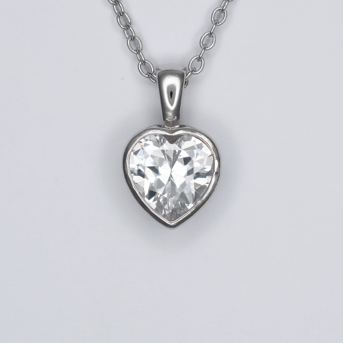 Heart shape silver pendant featuring a sparkling clear gemstone on a delicate chain