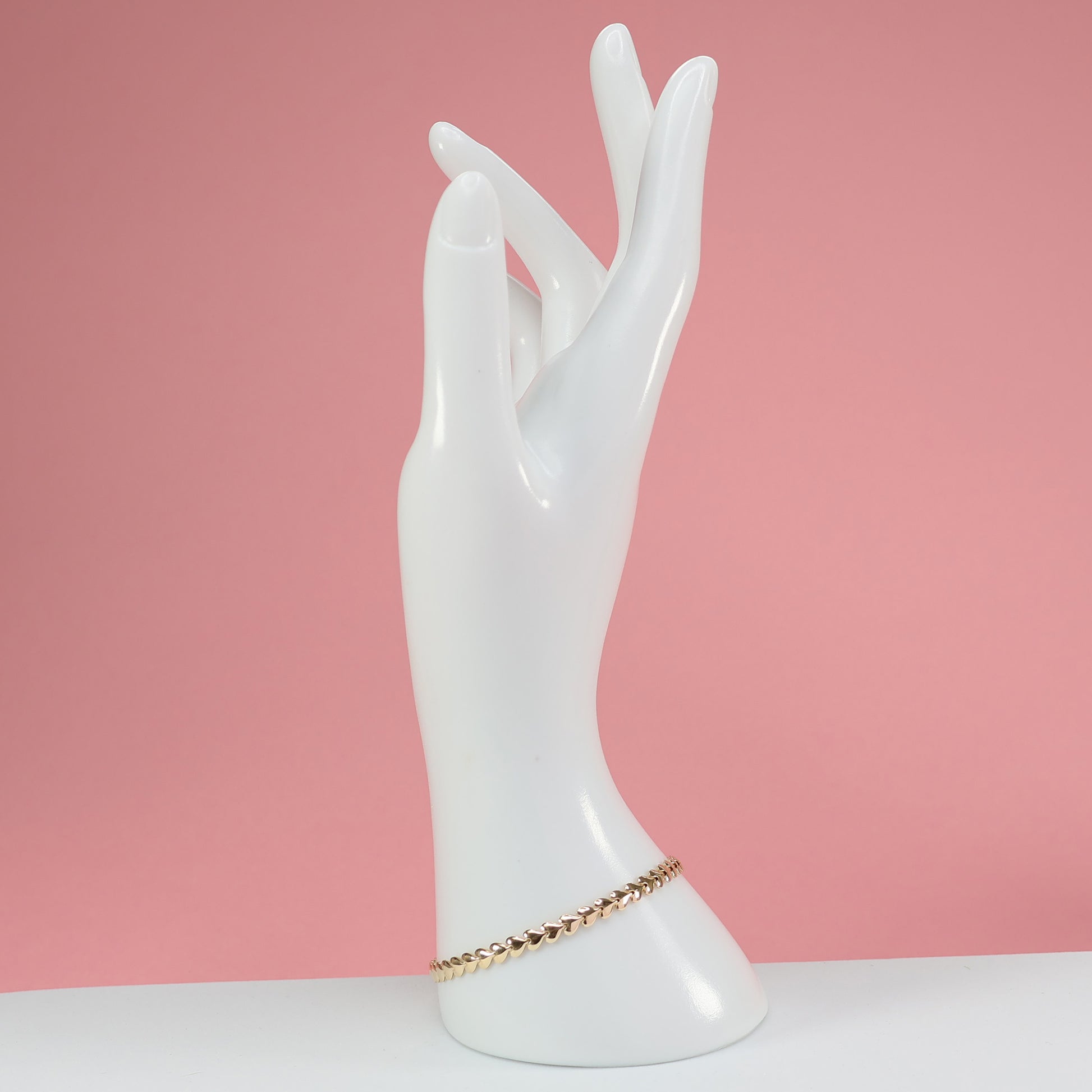 Elegant heart link bracelet for her displayed on a white mannequin hand against a pink background
