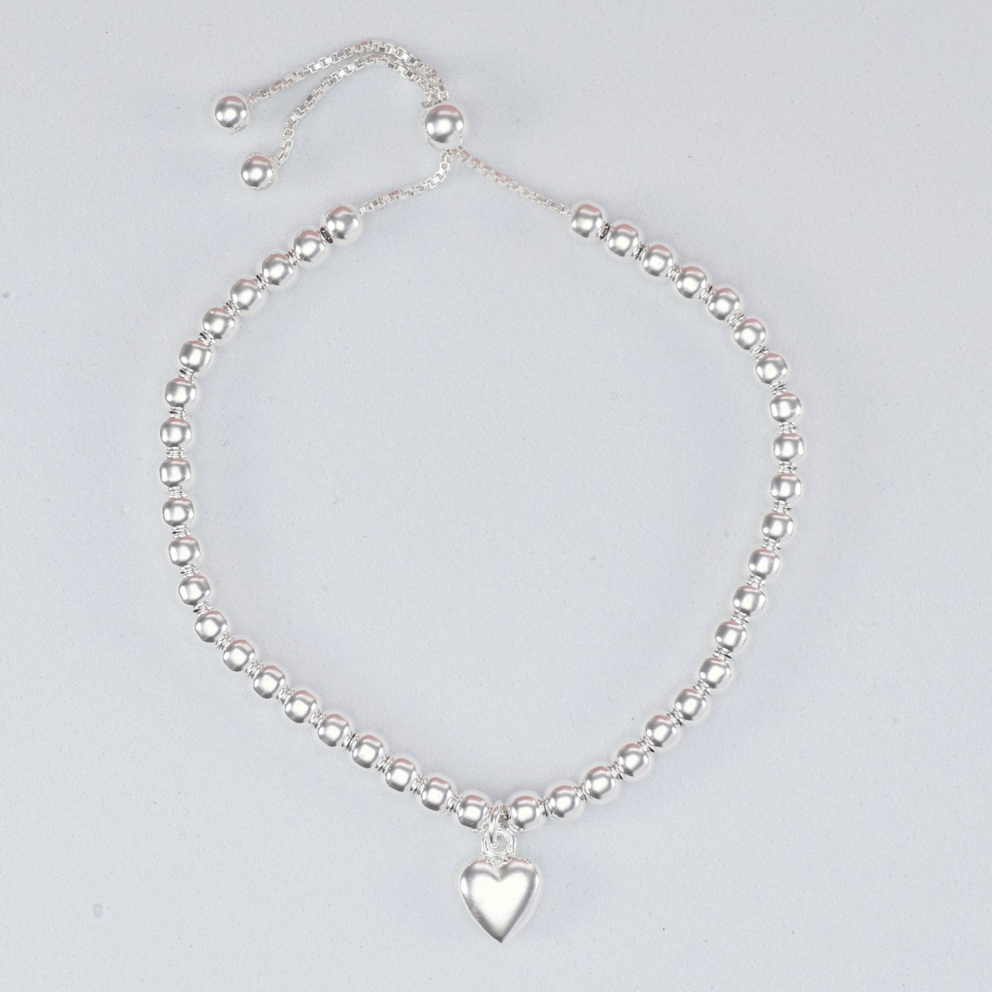 Silver bead heart charm bracelet featuring a polished heart pendant and adjustable sliding clasp