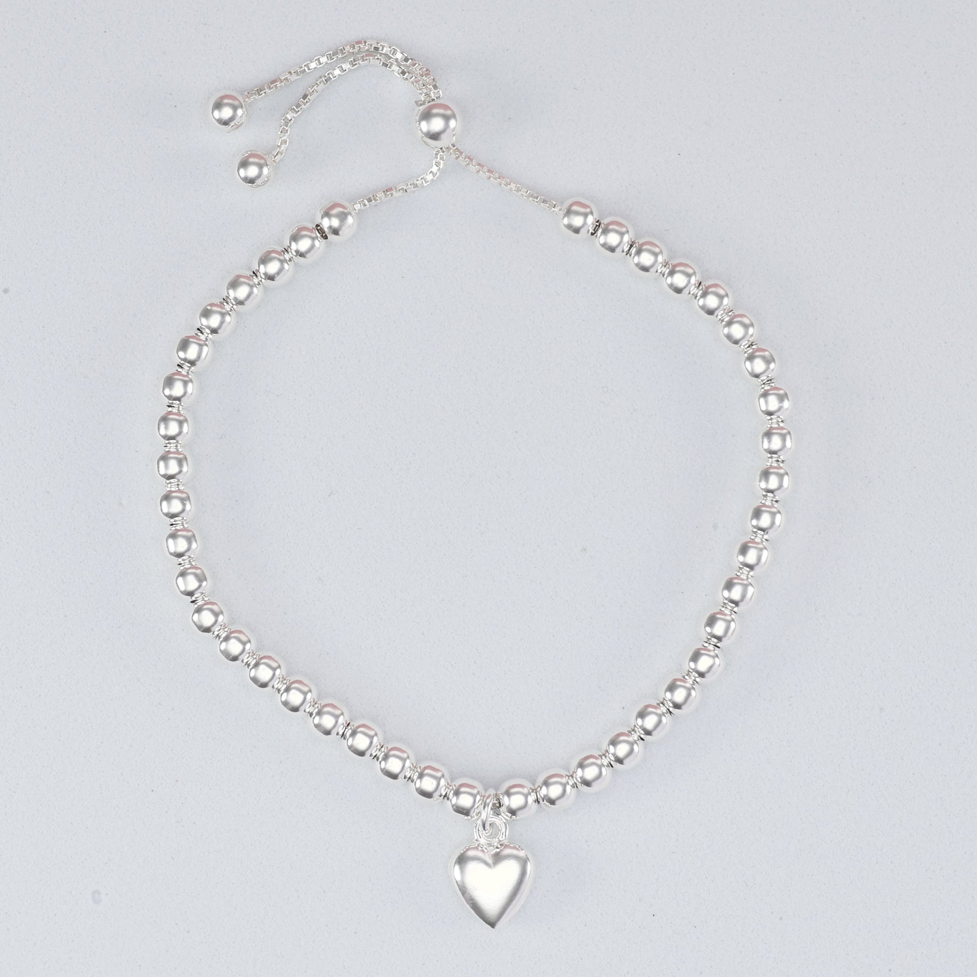 Silver bead heart charm bracelet featuring a polished heart pendant and adjustable sliding clasp
