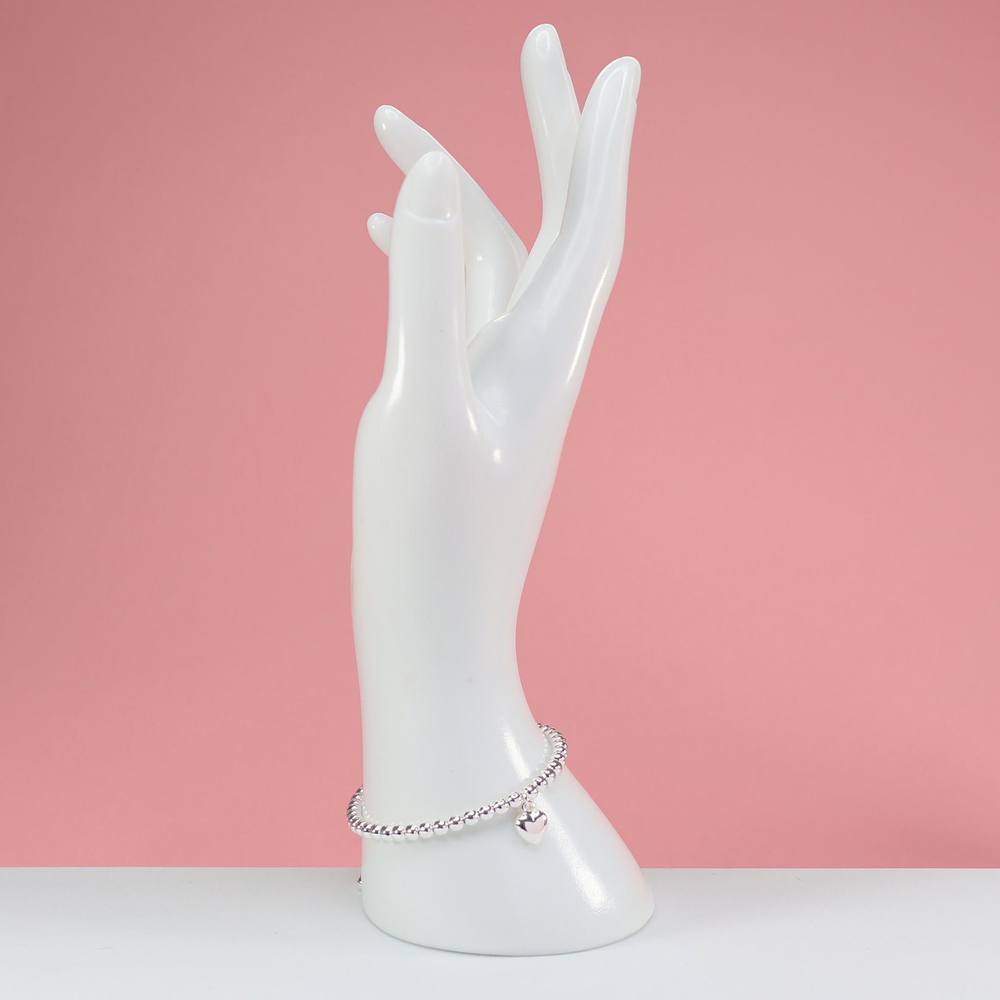 Stylish silver bead heart charm bracelet showcased on a decorative hand display