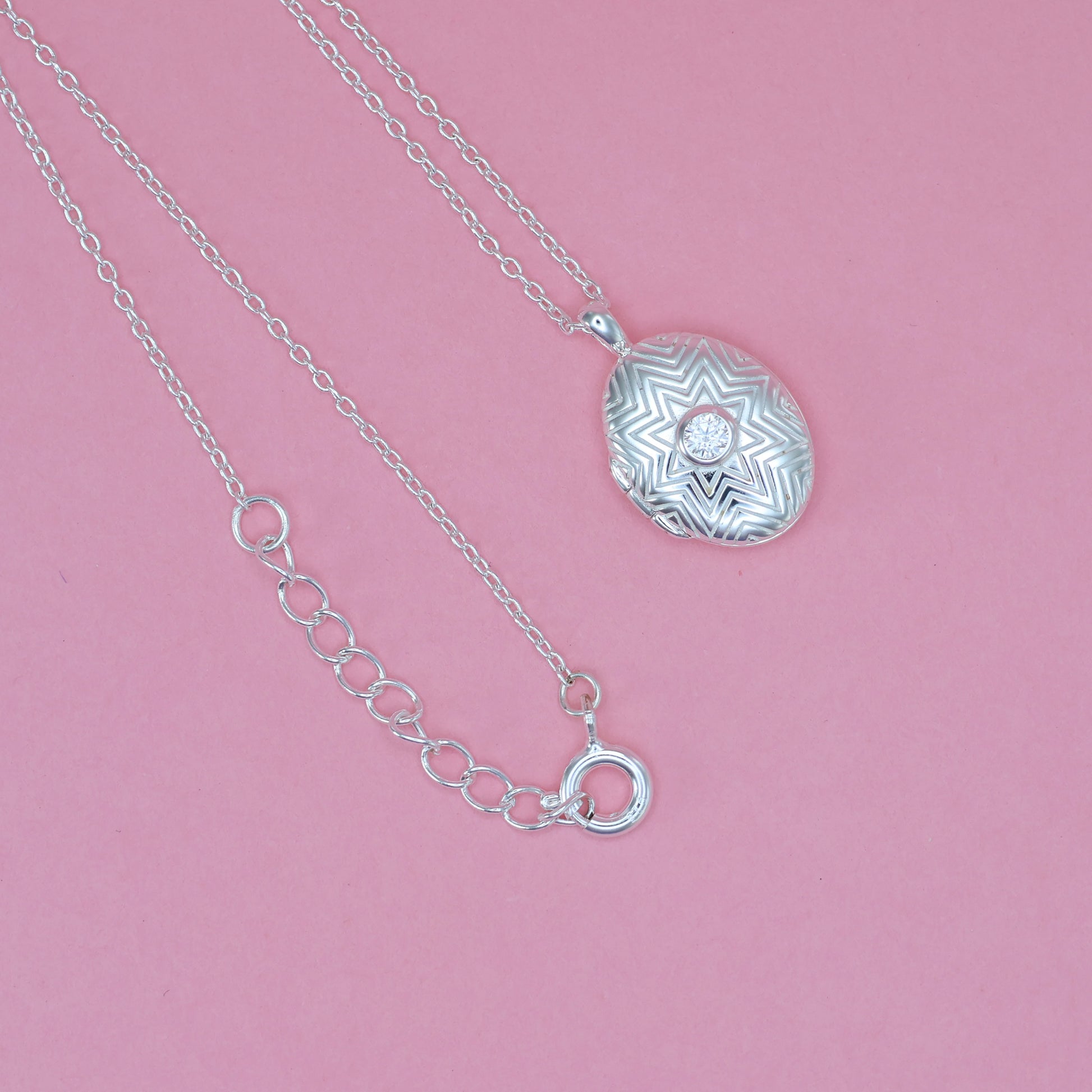 Stunning silver oval locket necklace featuring intricate design and a sparkling centerpiece