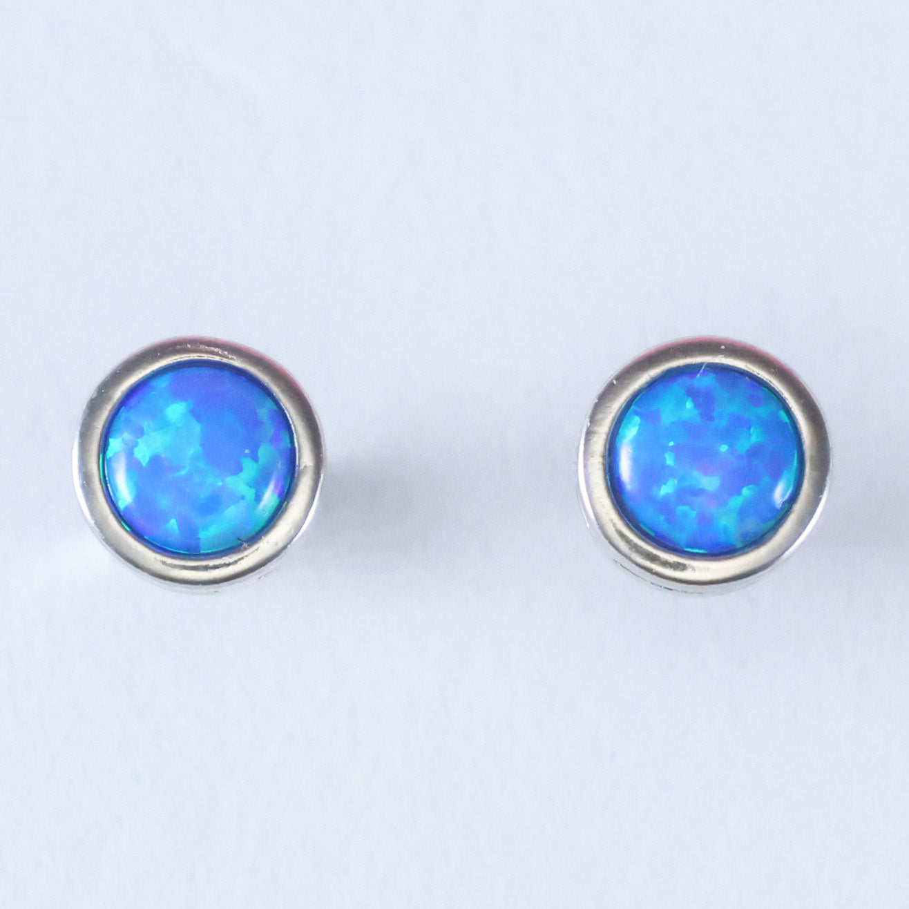 Elegant silver stud earrings for women featuring a vibrant blue opal centerstone
